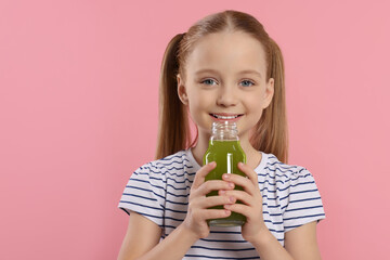 Little girl drinking fresh juice on pink background. Space for text