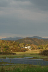 Fototapeta premium View of village in Norway surrounded by mountains at sunset after rain