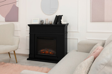 Black stylish fireplace near comfortable sofa in cosy living room