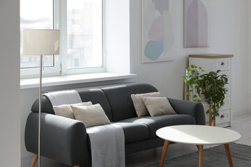 Gray couch with pillows, white coffee table and lamp in living room