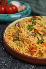 Delicious pilaf with meat and ingredients on black textured table, closeup