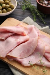 Slices of delicious ham with thyme on dark wooden table