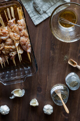 Marinating raw chicken skewers surrounded by ingredients for marinating.