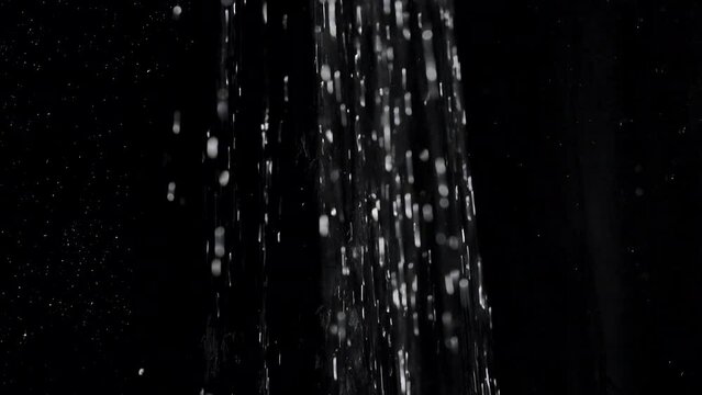 Running water from a shower head pouring down on a black background