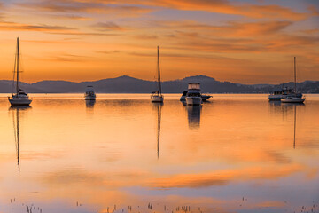 Fototapeta na wymiar Beautiful sunrise waterscape with high cloud, reflections and boats
