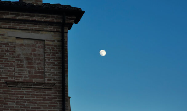 Luna di sera tra le case