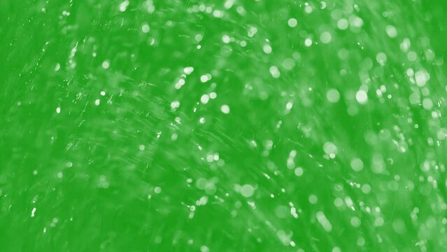Water stream with dreamy bokeh from shower head splashes spray on window green screen background