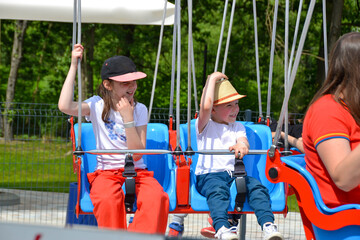 Kids having fun in ferris wheel with chains, carousel ski flyer in amusement park