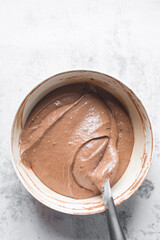 Chocolate cake batter in a white mixing bowl, cake batter in a white ceramic mixing bowl, the process of making chocolate cake