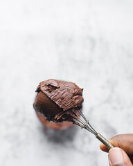 Cocoa powder mixed into a paste with a whisk, clumpy cocoa powder paste in a small transparent bowl