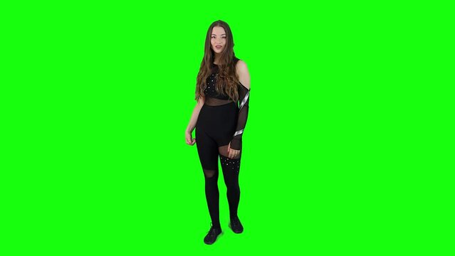 Slow motion full body view on an attractive female model wearing a body outfit whistling in front of a green screen