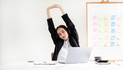 Asian female accountant is tired from working in a chair, stretching to relax and relax while...