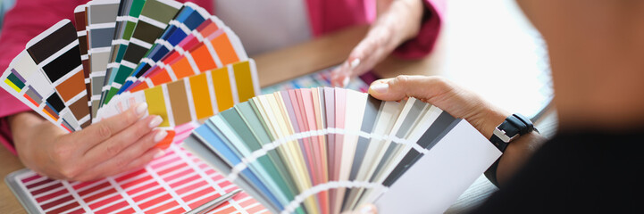Manager helps client choose color from variety of samples in office.
