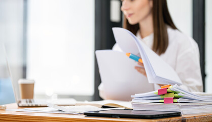 Closeup woman working in Stacks of paper files for searching and checking unfinished document...