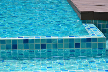 surface of blue swimming pool with brown wood balcony, freshness water background