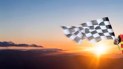 Fotobehang Formule 1 Checkered race flag in hand against sunset sky  © xy