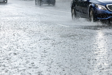 car traffic on flooded city road during rain. water splashing from car wheels.