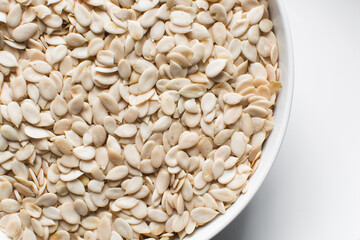 top view of nigerian egusi seeds in a white bowl, closeup of shelled melon seeds in a bowl, nigerian melon seeds, pumpkin seeds for cooking	