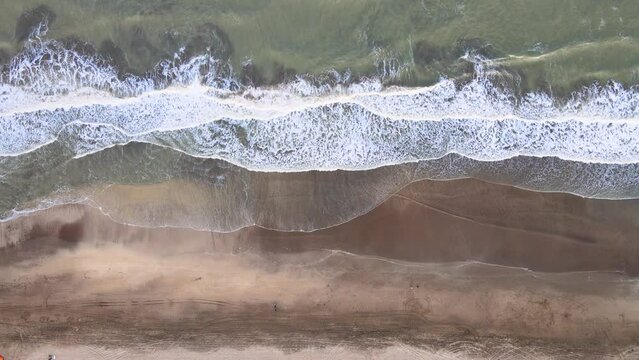 Static top down drone shot of a beach in Caril&oacute;, Argentina with waves crashing on the shore.