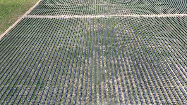 Solar panel array on large solar energy farm in USA. Clean, green, and renewable energy for cities in America. Aerial tilt up reveal.