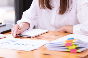 Hand of a businesswoman working with papers and documents at a desk in the office.