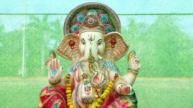 RichStatue Of God Lord Ganesha. Colorful Statue. Elephant Face God. Green Background. Main Hindu God. Hinduism Religion and Culture.	