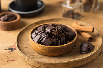 Cubes of dark artisan chocolate in a wooden bowl. Bitter chocolate