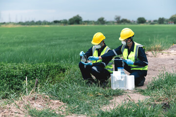 Two Environmental Engineers Inspect Water Quality and Take Water Samples Notes in The Field Near Farmland, Natural Water Sources maybe Contaminated by Toxic Waste or Suspicious Pollution Sites.