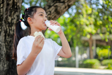 Little kid girl asian holding a bottle of milk in the school. feel happy and enjoy drinking milk before entering the classroom.