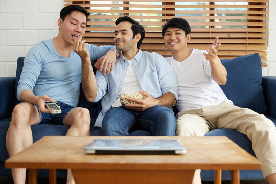 group of men watching tv and eating popcorn in living room