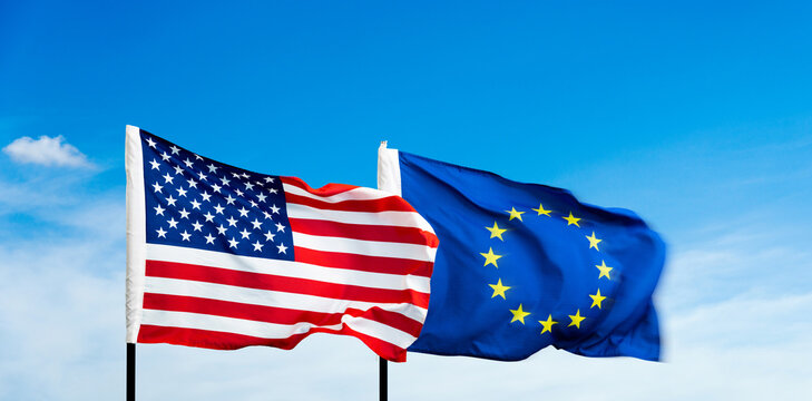 USA and European Union flags against blue sky background