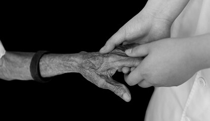 Young hands holding an old woman's wrinkled hands
