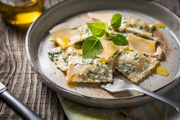 Ravioli with ricotta cheese, parmesan and spinach. Garnished with basil leaves and olive oil. Fresh and tasty classic Italian pasta dish.