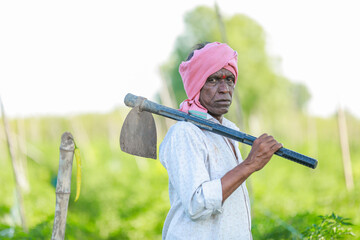 Happy Indian farmer, holding farming tools in hand