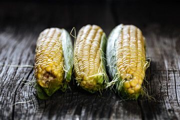 Fresh, raw corn placed on a wooden board in dark rustic atmosphere