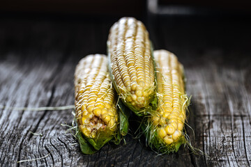 Fresh, raw corn placed on a wooden board in dark rustic atmosphere