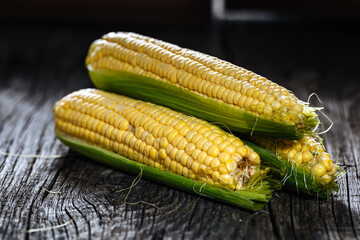 Fresh, raw corn placed on a wooden board in dark rustic atmosphere