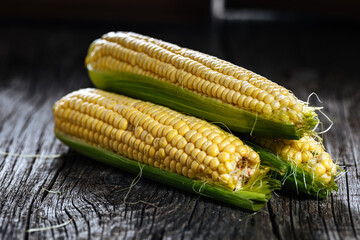 Fresh, raw corn placed on a wooden board in dark rustic atmosphere