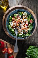 Salad with chicken, cheese, tomato and arugula. Healthy meal from superfood, rich with vitamins and minerals. Placed on wooden board.