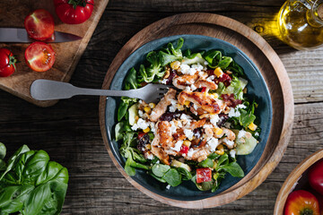 Salad with chicken, cheese, tomato and arugula. Healthy meal from superfood, rich with vitamins and minerals. Placed on wooden board.