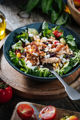 Salad with chicken, cheese, tomato and arugula. Healthy meal from superfood, rich with vitamins and minerals. Placed on wooden board.
