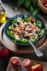 Salad with chicken, cheese, tomato and arugula. Healthy meal from superfood, rich with vitamins and minerals. Placed on wooden board.