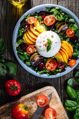 Salad with burrata cheese, peaches, tomato, plum, cherries and arugula. Italian healthy meal with lot of vitamins. Super food.