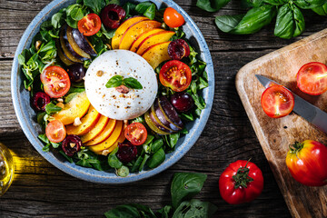 Salad with burrata cheese, peaches, tomato, plum, cherries and arugula. Italian healthy meal with lot of vitamins. Super food.