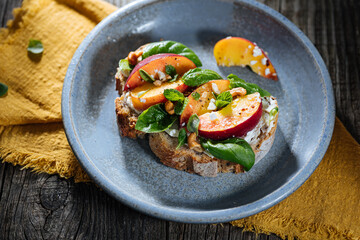 Spread with cream cheese on bread with rucola, nuts and peach. Healthy summer brunch. Vitamins and minerals