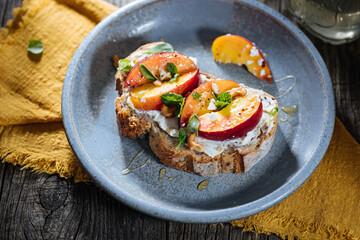 Spread with cream cheese on bread with rucola, nuts and peach. Healthy summer brunch. Vitamins and minerals