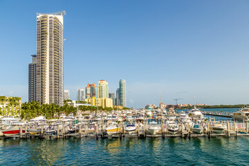 Fototapeta na wymiar Miami skyline at daytime with blue sky and view to pier with motor boats