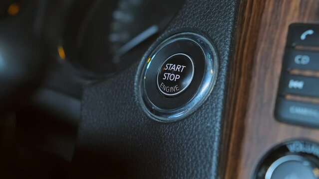 Male hand starting car with button, close up. Man hand pushing start stop button in car. Closeup male driver using start button in modern car.