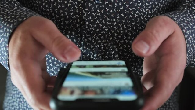 Man use of mobile phone closeup. Hands of person quickly flipping through tape on Internet view on social network with fingers.