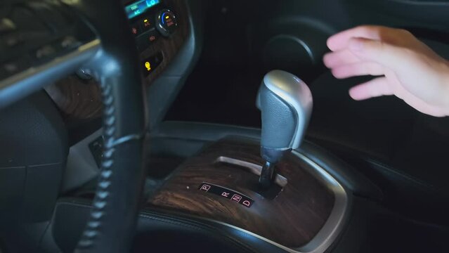 Person changing speed by hand holding gearbox in car, driver shifting gears. Start road trip exit parking lot. European male driving car moving transmission shifting automatic transmission